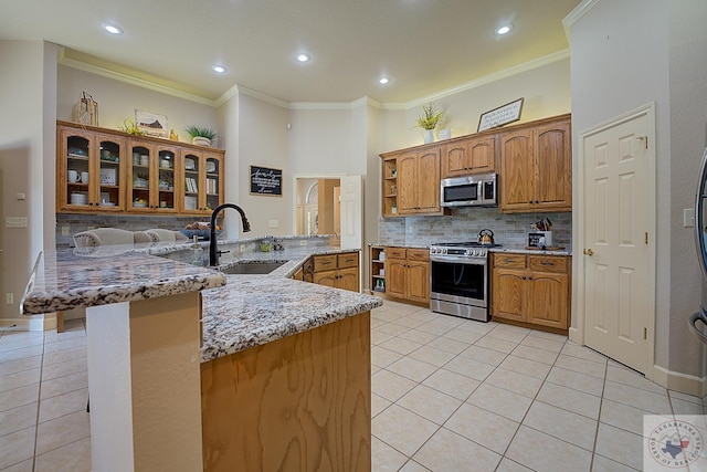 kitchen featuring sink, light tile patterned floors, kitchen peninsula, and appliances with stainless steel finishes