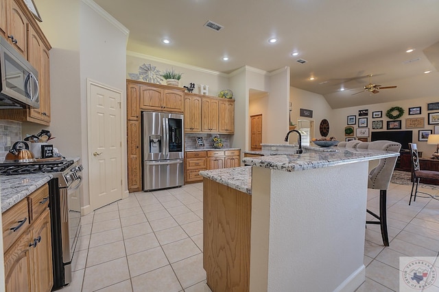 kitchen featuring a center island with sink, a breakfast bar, light tile patterned flooring, and appliances with stainless steel finishes