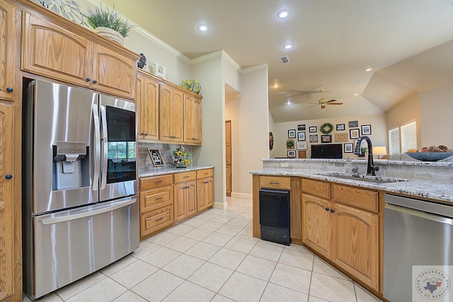 kitchen featuring light stone countertops, stainless steel appliances, sink, ornamental molding, and light tile patterned floors