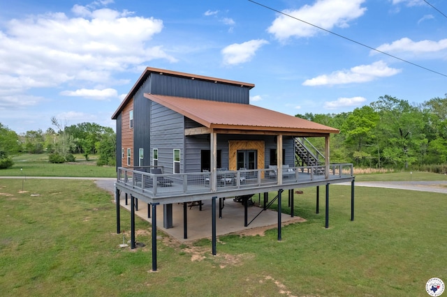 back of property with a wooden deck, a lawn, metal roof, stairway, and a patio