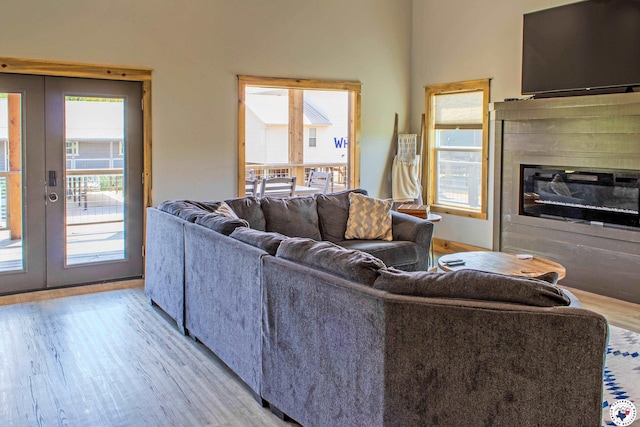living area with light wood-type flooring, french doors, and a glass covered fireplace