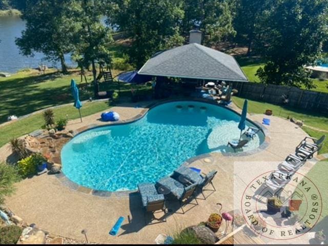 view of pool with an outdoor structure, a patio, a water view, and a yard