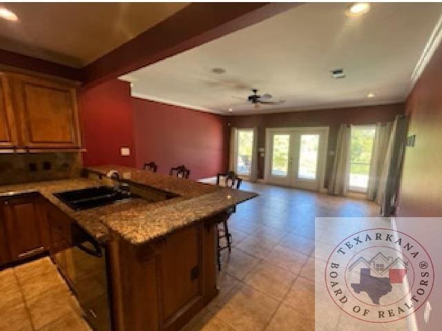 kitchen with a kitchen bar, french doors, sink, ceiling fan, and crown molding