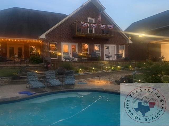 pool at dusk featuring a patio area