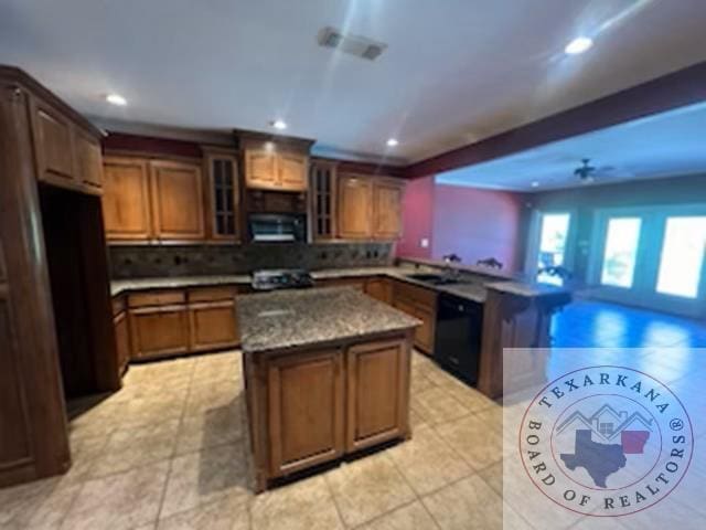 kitchen featuring sink, tasteful backsplash, light tile patterned floors, a center island, and black dishwasher