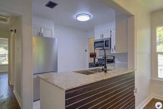 4201 Pine St, Texarkana, TX 75501 - kitchen featuring stainless steel appliances, wood finished floors, a peninsula, white cabinetry, and plenty of natural light