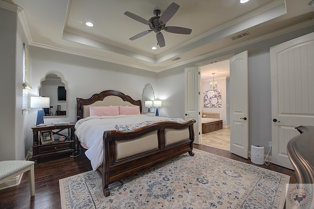 bedroom featuring ornamental molding, ceiling fan with notable chandelier, connected bathroom, dark hardwood / wood-style floors, and a tray ceiling