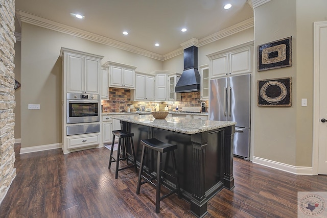 kitchen with a center island, appliances with stainless steel finishes, tasteful backsplash, premium range hood, and light stone counters