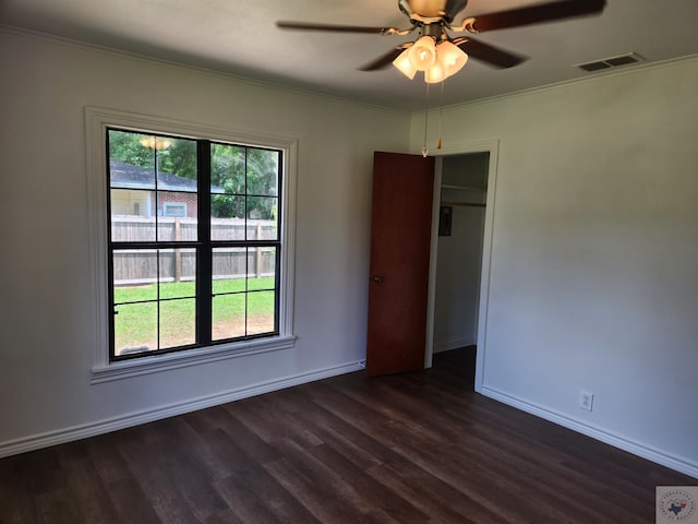 empty room featuring ceiling fan, dark hardwood / wood-style floors, ornamental molding, and plenty of natural light