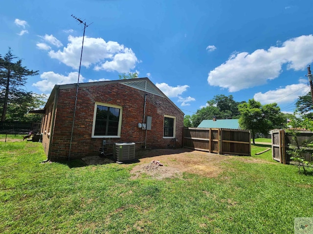 back of house with central AC unit and a yard