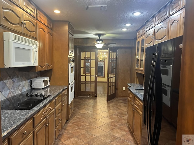 kitchen featuring a textured ceiling, black electric stovetop, dark stone counters, decorative backsplash, and ceiling fan