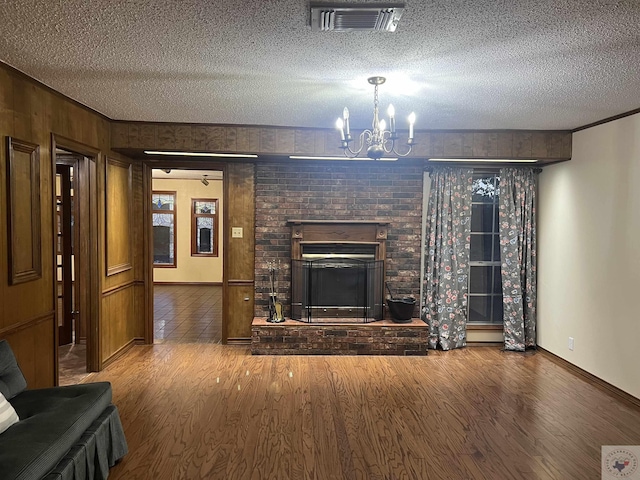 unfurnished living room with hardwood / wood-style flooring, a textured ceiling, an inviting chandelier, and a fireplace