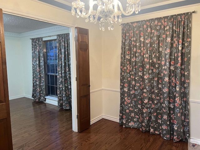 spare room featuring ornamental molding, a chandelier, a textured ceiling, and dark hardwood / wood-style flooring