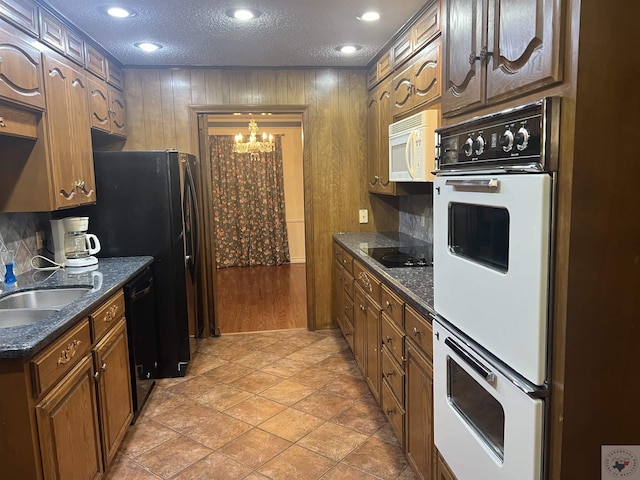 kitchen featuring a textured ceiling, black appliances, an inviting chandelier, sink, and light tile patterned floors