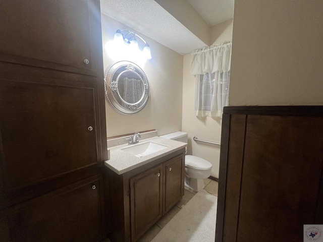 bathroom with a textured ceiling, toilet, tile patterned flooring, and vanity