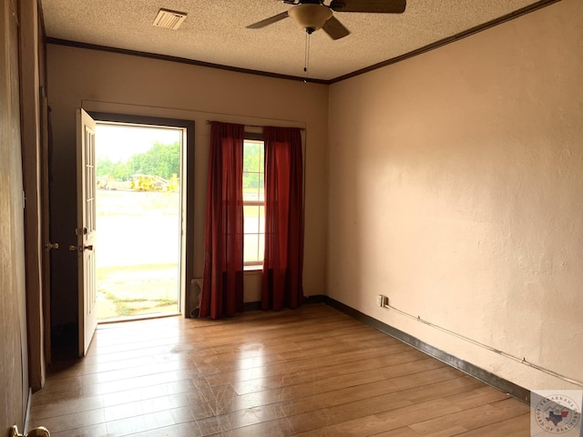 unfurnished room featuring ceiling fan, a textured ceiling, ornamental molding, and light wood-type flooring