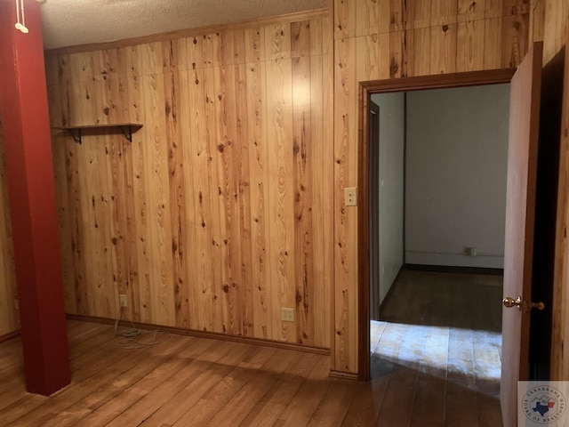 interior space with hardwood / wood-style floors, a textured ceiling, and wood walls