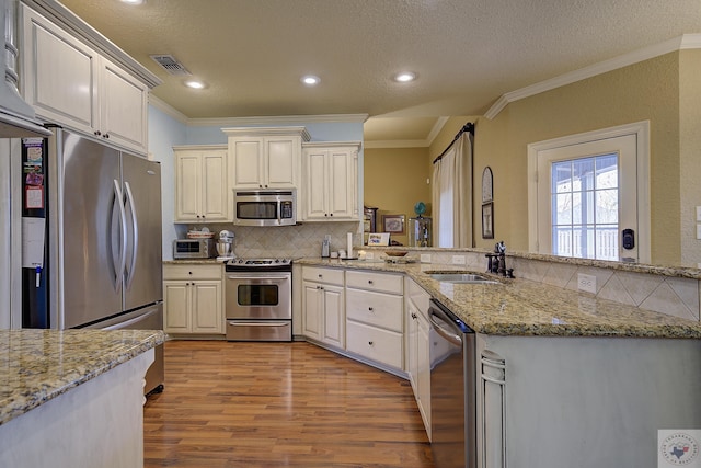 kitchen featuring sink, stainless steel appliances, light stone counters, and light hardwood / wood-style floors