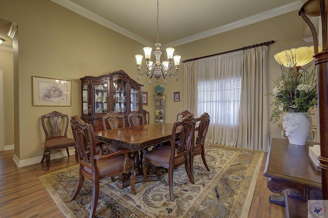 dining area with hardwood / wood-style flooring, an inviting chandelier, and ornamental molding