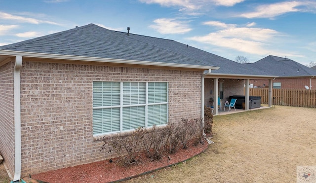 view of property exterior featuring a jacuzzi, a yard, and a patio