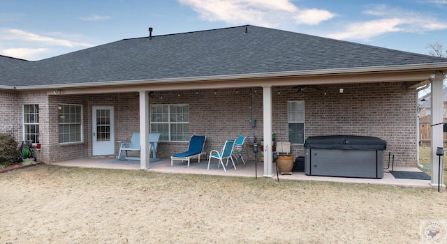 rear view of property with a patio area, a yard, and a hot tub