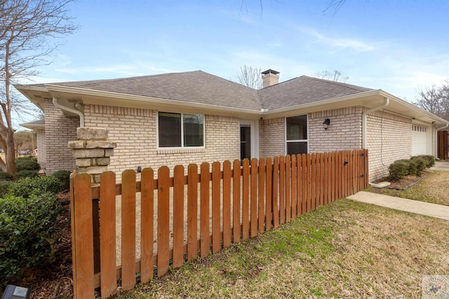 view of front of property with a garage, brick siding, a chimney, and fence