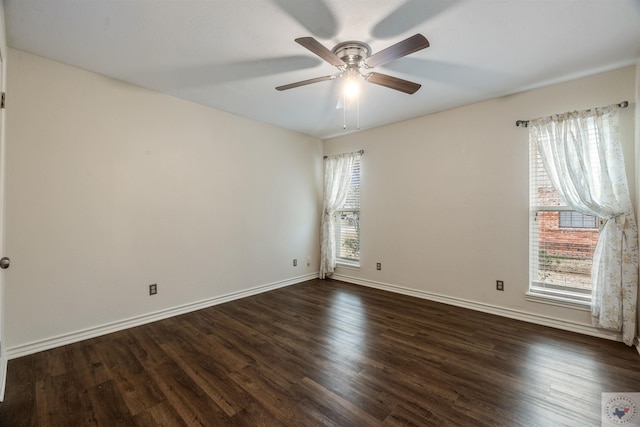 empty room with dark wood-style floors, plenty of natural light, and baseboards