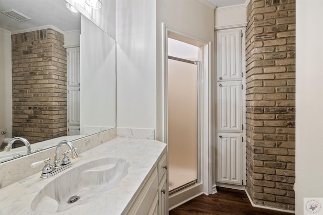 bathroom featuring visible vents, brick wall, ornamental molding, wood finished floors, and vanity