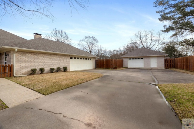 view of property exterior featuring brick siding, a yard, roof with shingles, fence, and an outdoor structure