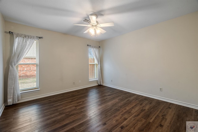 empty room featuring dark wood-style floors, ceiling fan, visible vents, and baseboards