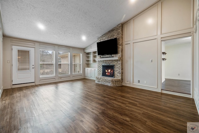 unfurnished living room with a brick fireplace, built in shelves, a decorative wall, and a textured ceiling