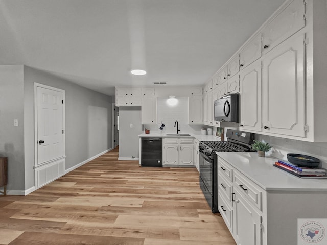 kitchen with black appliances, white cabinetry, light hardwood / wood-style floors, and sink