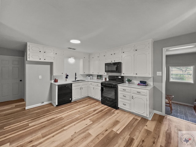 kitchen with black appliances, white cabinetry, sink, backsplash, and light wood-type flooring