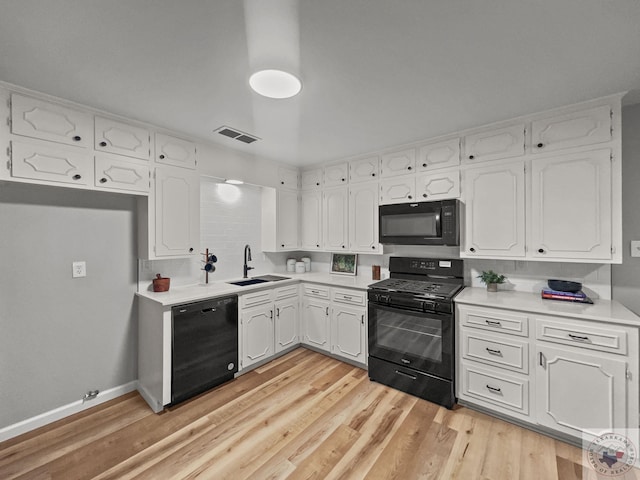 kitchen featuring sink, black appliances, light wood-type flooring, and white cabinets