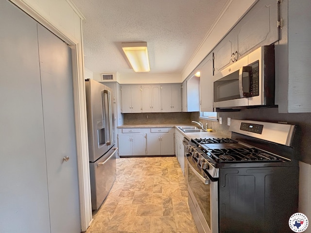 3703 Hickory St, Texarkana, AR 71854 - kitchen with appliances with stainless steel finishes, gray cabinetry, a textured ceiling, stone finish floors, and ornamental molding