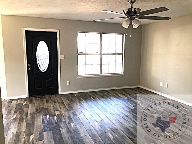 foyer entrance with a ceiling fan, a textured ceiling, baseboards, and wood finished floors