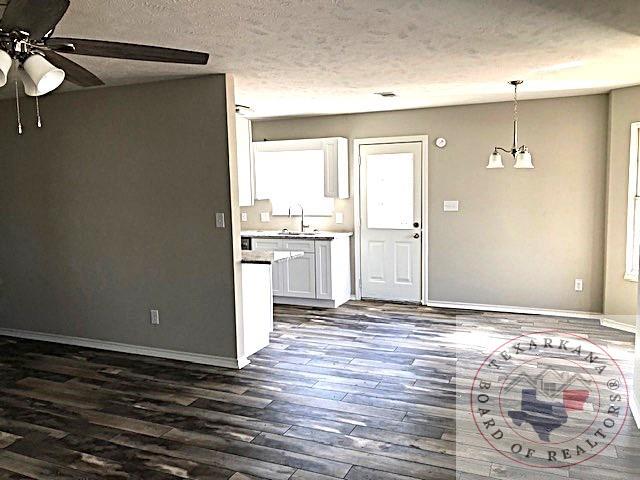 interior space featuring dark wood finished floors, white cabinets, a sink, a textured ceiling, and baseboards