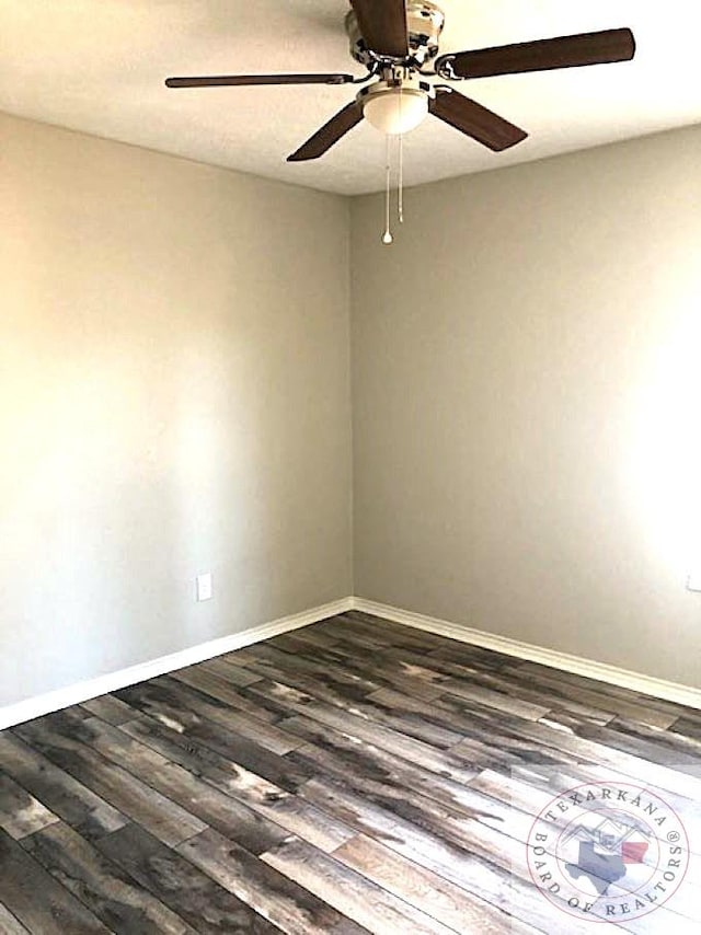 empty room featuring ceiling fan, baseboards, and dark wood-type flooring