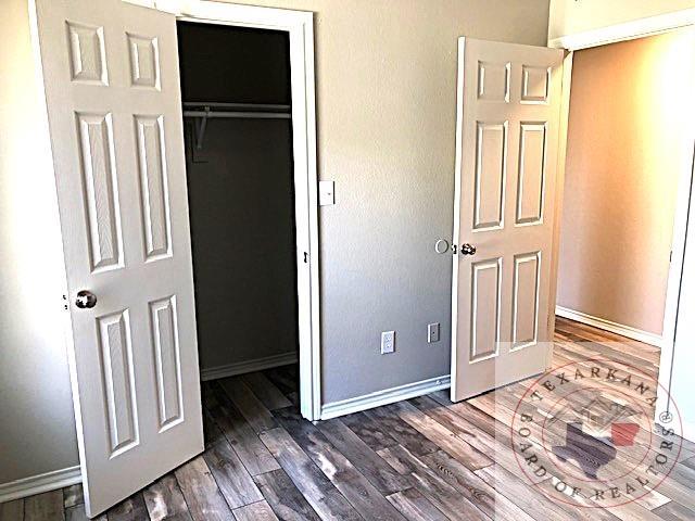 unfurnished bedroom with a spacious closet, baseboards, a closet, and wood finished floors