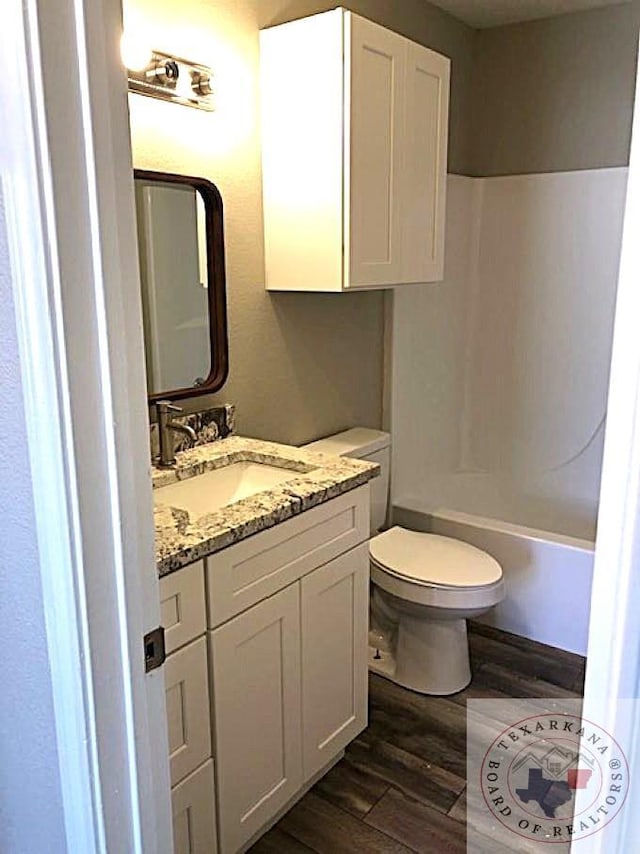 full bathroom featuring tub / shower combination, vanity, toilet, and wood finished floors