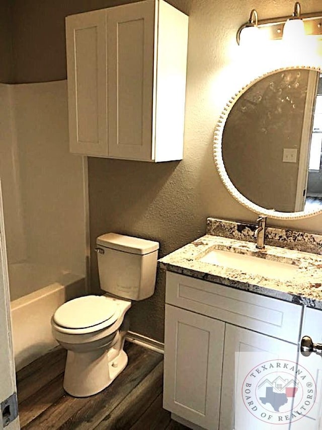 full bathroom featuring a textured wall, vanity, wood finished floors, and toilet