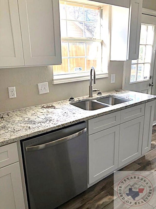 kitchen featuring dark wood-style floors, light stone counters, white cabinets, a sink, and dishwasher