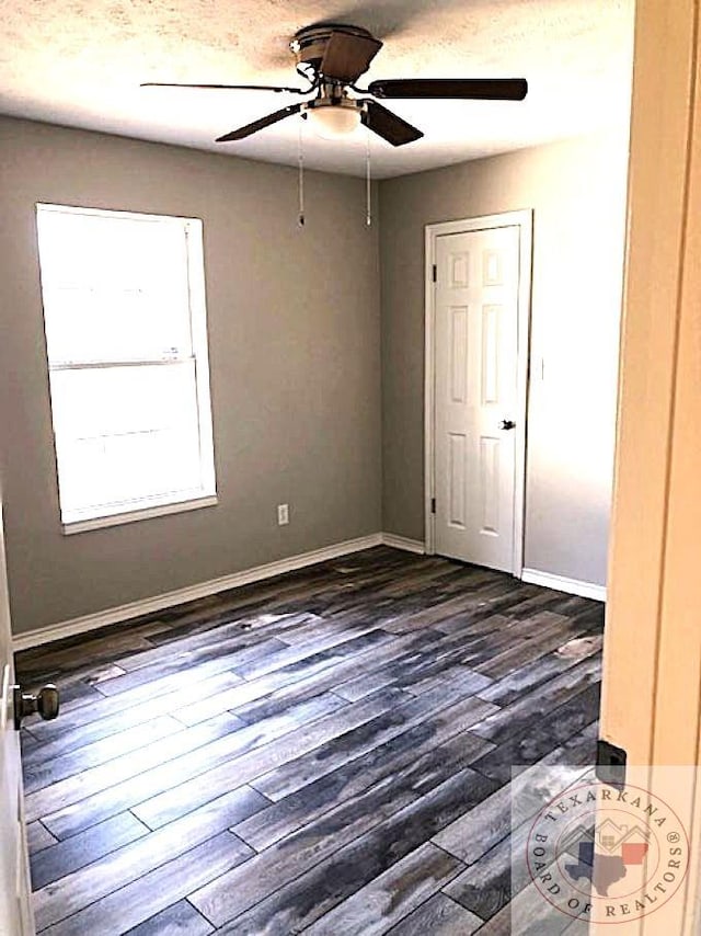 spare room featuring a ceiling fan, dark wood-style flooring, a textured ceiling, and baseboards