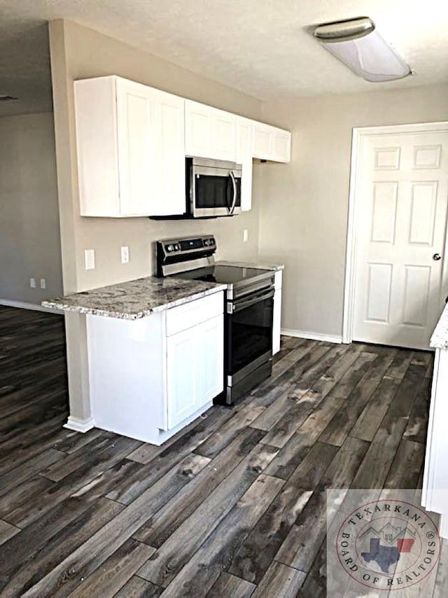 kitchen with white cabinets, dark stone countertops, dark hardwood / wood-style floors, and appliances with stainless steel finishes