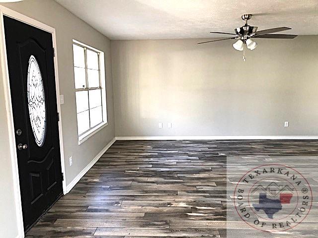 foyer with ceiling fan, a textured ceiling, baseboards, and wood finished floors