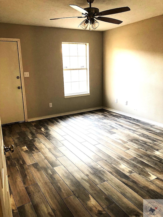 spare room with dark wood-type flooring, baseboards, and a ceiling fan