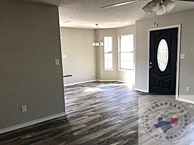 entryway with dark wood-type flooring, ceiling fan, a textured ceiling, and baseboards