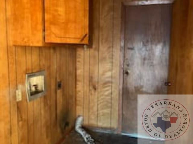 washroom featuring wooden walls and cabinets