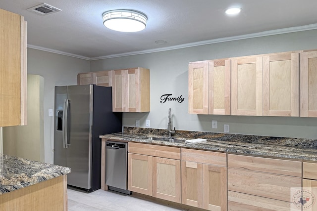 kitchen with dark stone countertops, ornamental molding, appliances with stainless steel finishes, and light brown cabinets