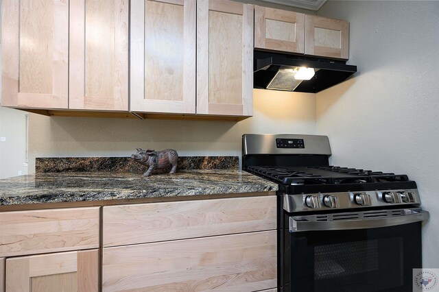 kitchen with stainless steel range with gas cooktop, light brown cabinets, and dark stone countertops